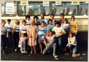 Women Against Pit Closures in their t-shirts in front of a bus to go demonstrate. Smiling and being silly. 