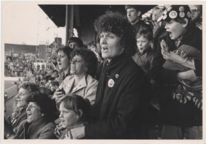 Women Against Pit Closures and children at a protest in what looks like a football stadium in 1985
