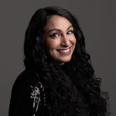 A woman with long black hair smiling to camera