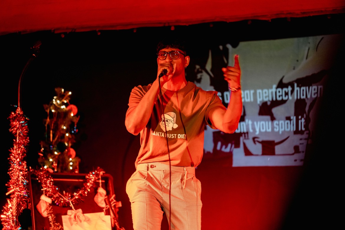 A man rapping in a Santa Must Die t-shirt